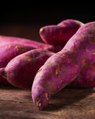 Close-up of purple sweet potatoes on a wooden surface, perfect for culinary and natural food themes.